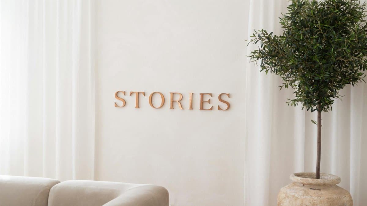 A cozy minimalist living room featuring a potted tree and 'Stories' wall decor.