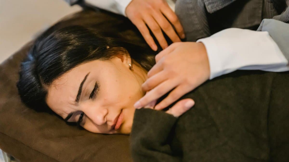 From above of young ethnic sad woman in casual clothes lying on knees of crop anonymous female friend and crying