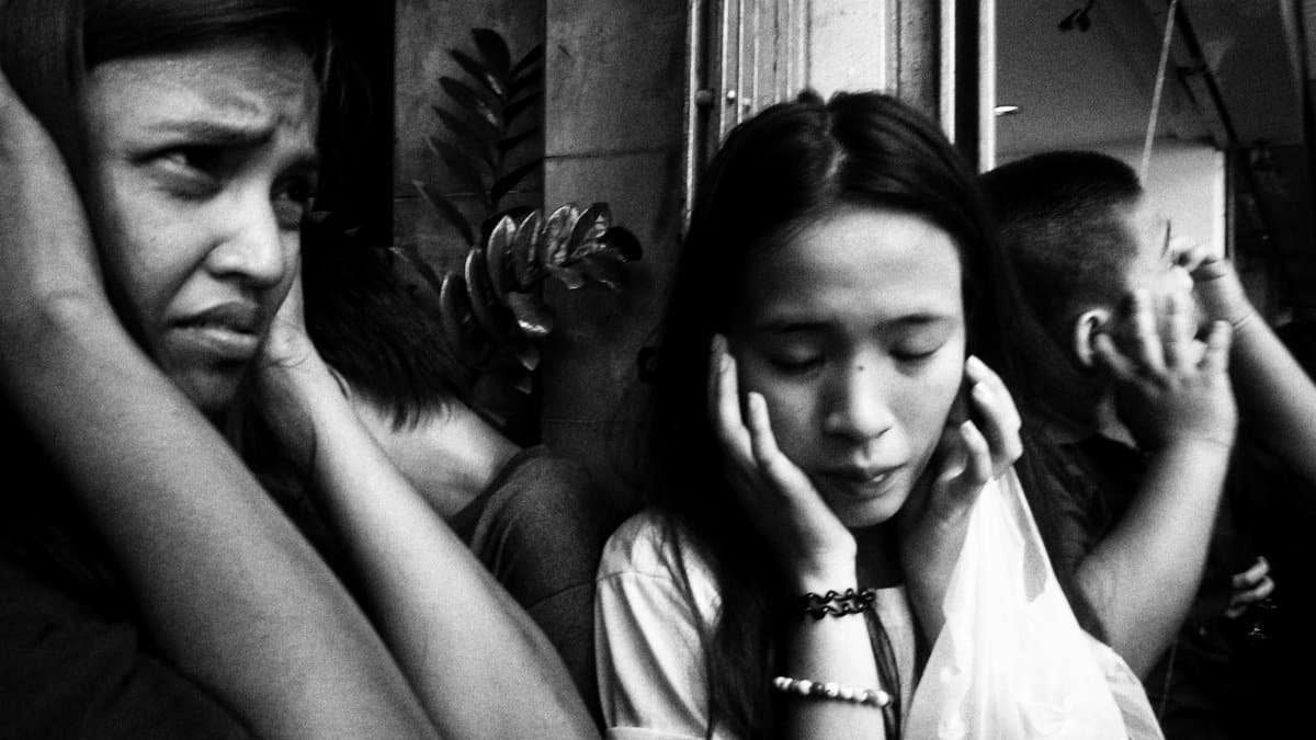 A diverse group of adults covers their ears in distress, illustrating overwhelming sound or noise.