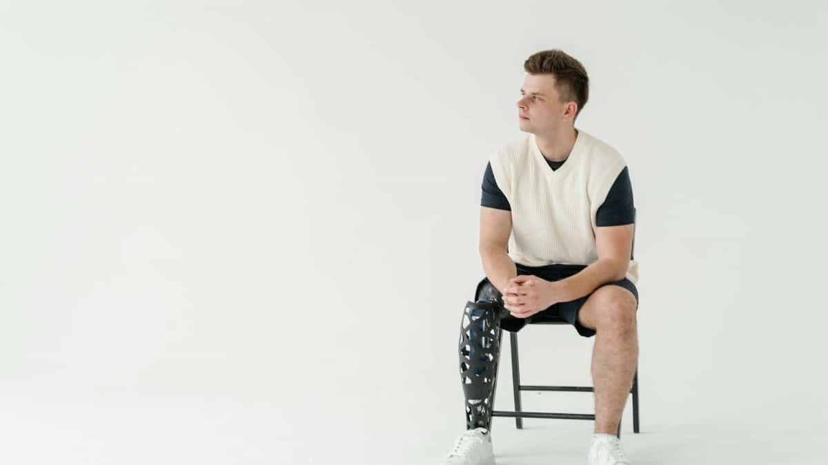 Man with a bionic prosthetic leg sitting in a minimalist room. Technology in everyday life.