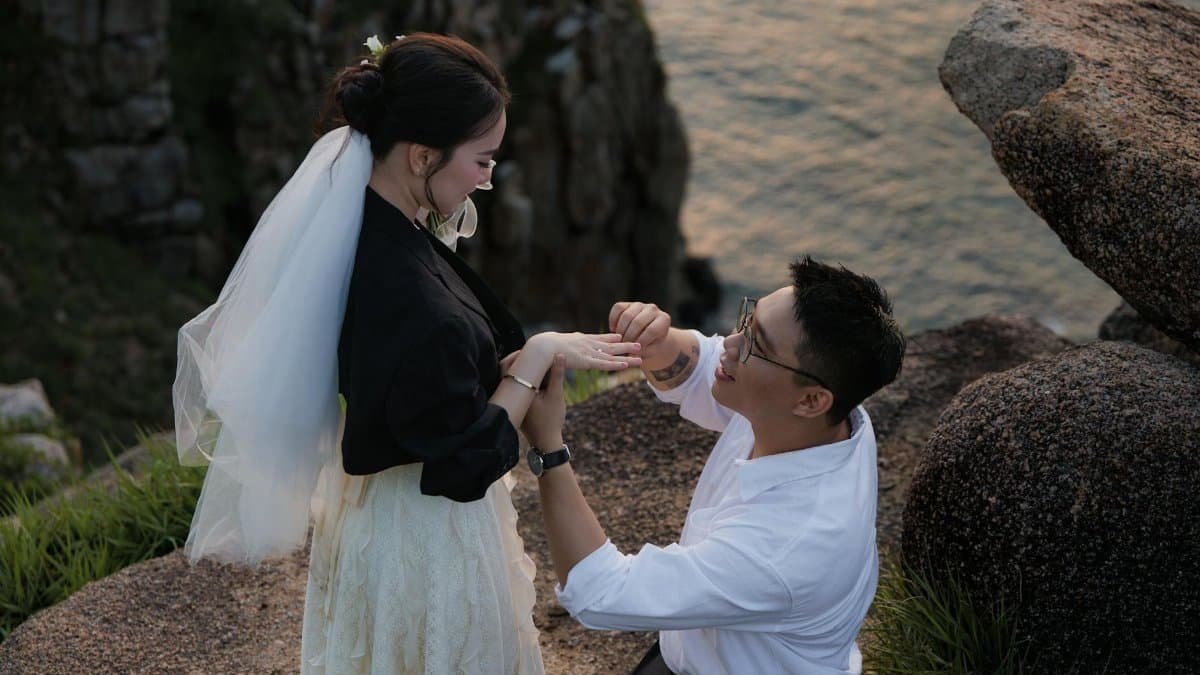 A man proposing to a woman on a cliffside during sunset, capturing a romantic moment.