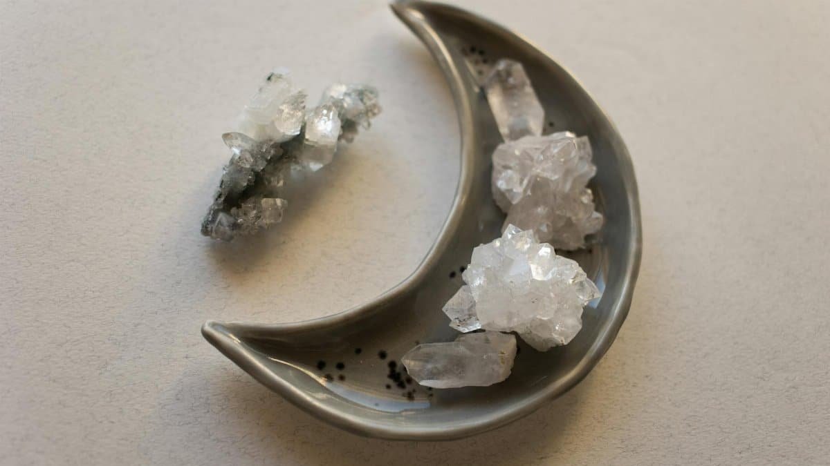 Decorative crystal stones arranged on a crescent-shaped dish, perfect for energy healing and decoration.