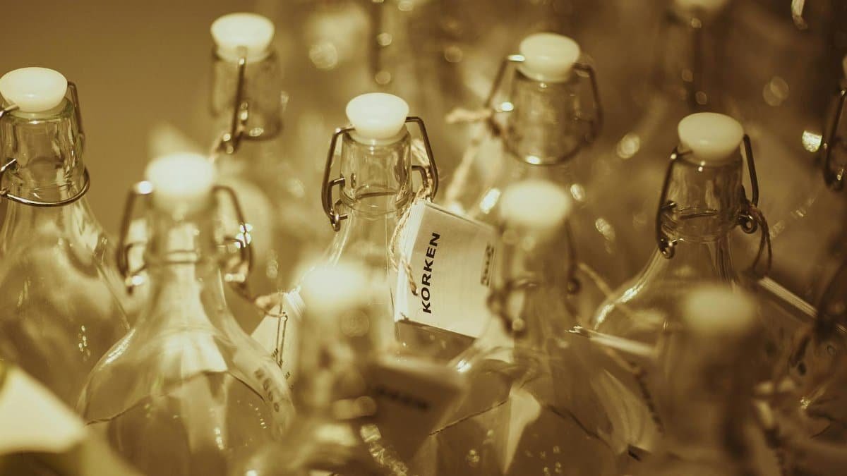 Closeup of empty glass bottles with white stoppers on display.