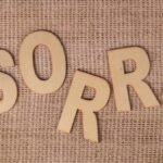 Wooden letters forming 'SORRY' on a burlap surface, offering a rustic apology vibe.