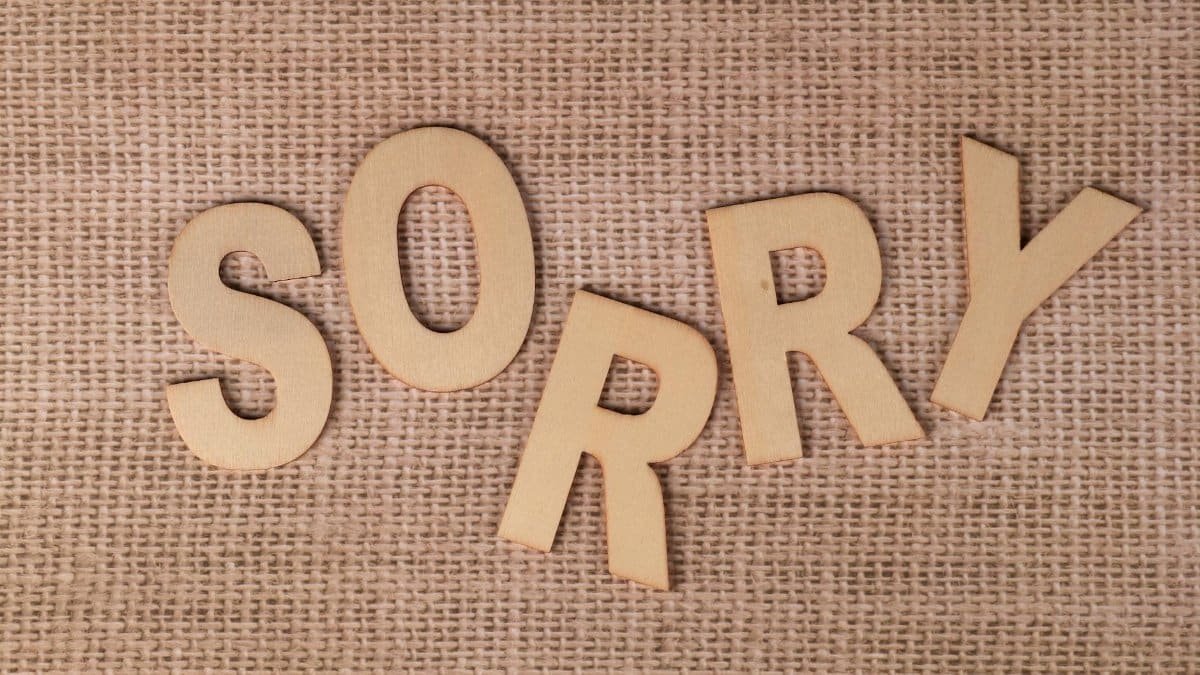 Wooden letters forming 'SORRY' on a burlap surface, offering a rustic apology vibe.