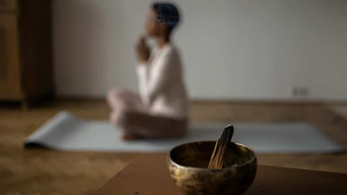 A serene indoor scene of meditation with an incense bowl and a woman practicing yoga.