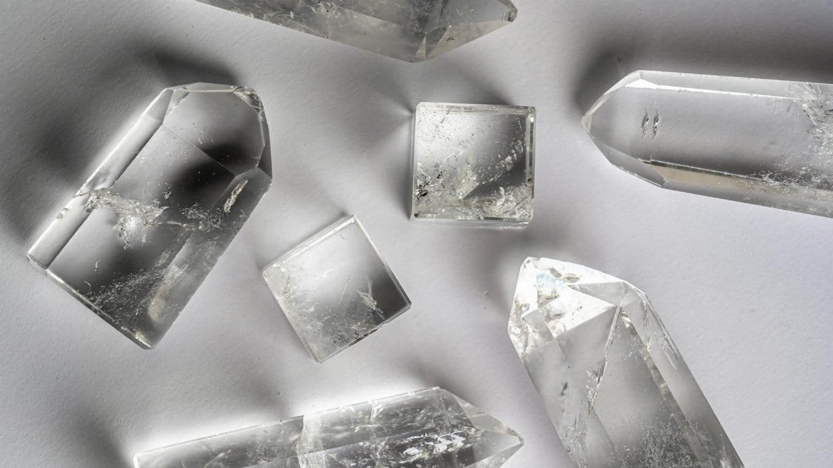 Clear quartz crystals arranged on a white surface, showcasing natural beauty and clarity.