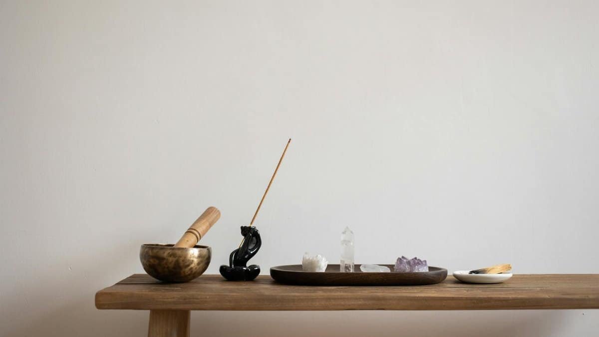 A serene setup featuring crystals, incense, and a singing bowl on a wooden table, perfect for meditation.