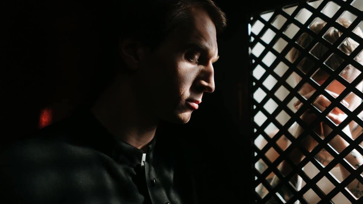 A contemplative priest listens to a confession in a dimly lit church setting, capturing a moment of faith and spirituality.