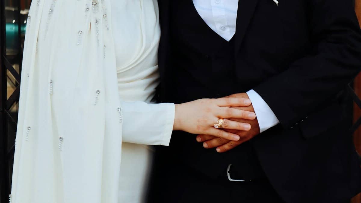Close-up of a couple holding hands dressed in elegant formal attire, symbolizing unity and love.