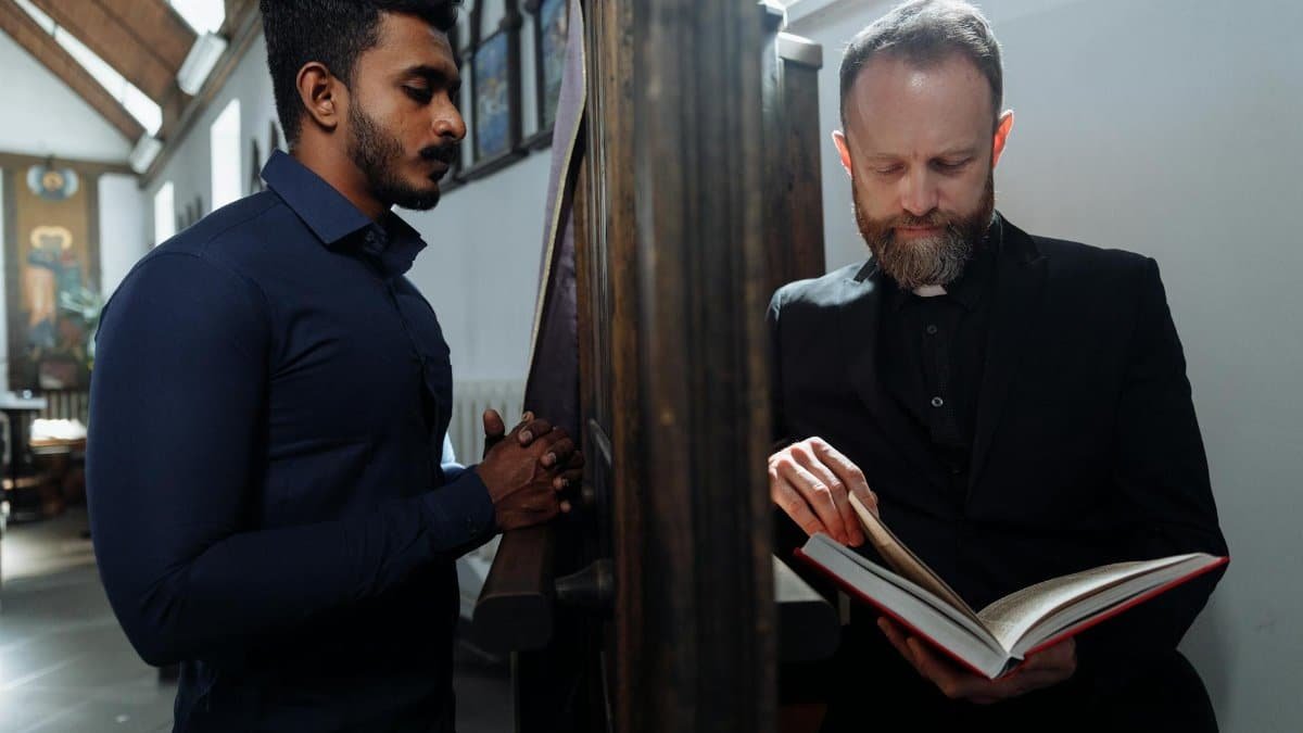 A solemn moment of confession between a devoted man and a priest in a church setting.