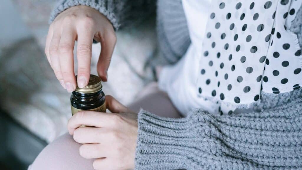 A close-up of hands opening a medicine bottle, emphasizing healthcare and recovery.