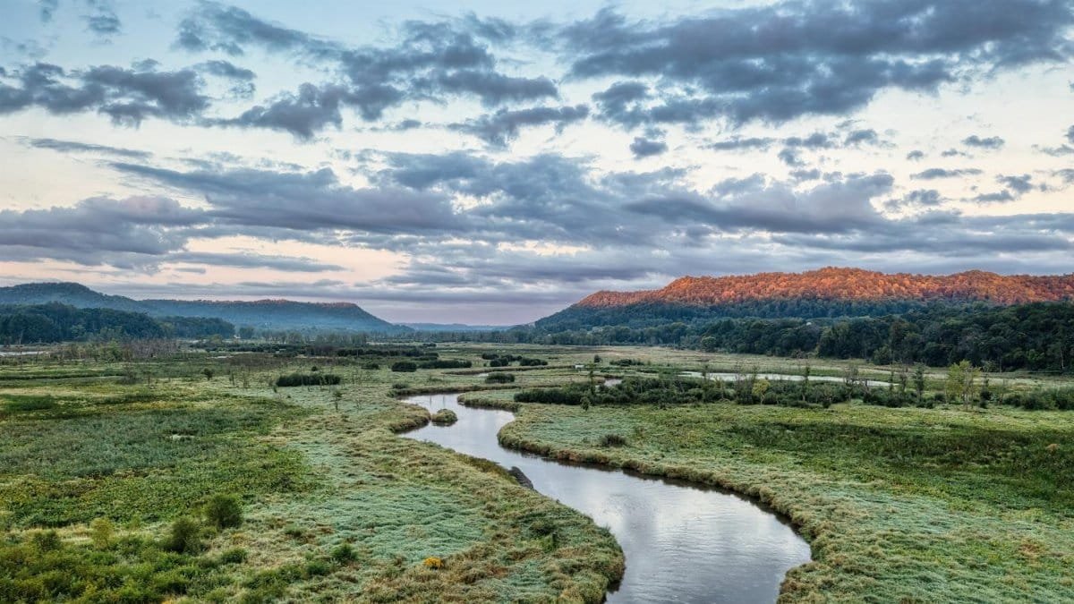 A peaceful landscape featuring a winding river and distant hills at dawn in Tell, Wisconsin.