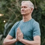 Serene elderly man meditating outdoors in a tranquil garden setting, focusing on peace and mindfulness.