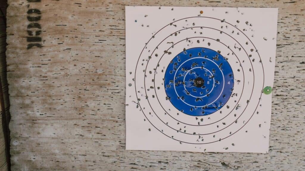 Close-up of a well-used archery target with numerous bullet holes in an outdoor setting.