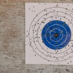 Close-up of a well-used archery target with numerous bullet holes in an outdoor setting.