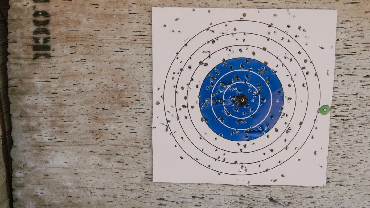 Close-up of a well-used archery target with numerous bullet holes in an outdoor setting.