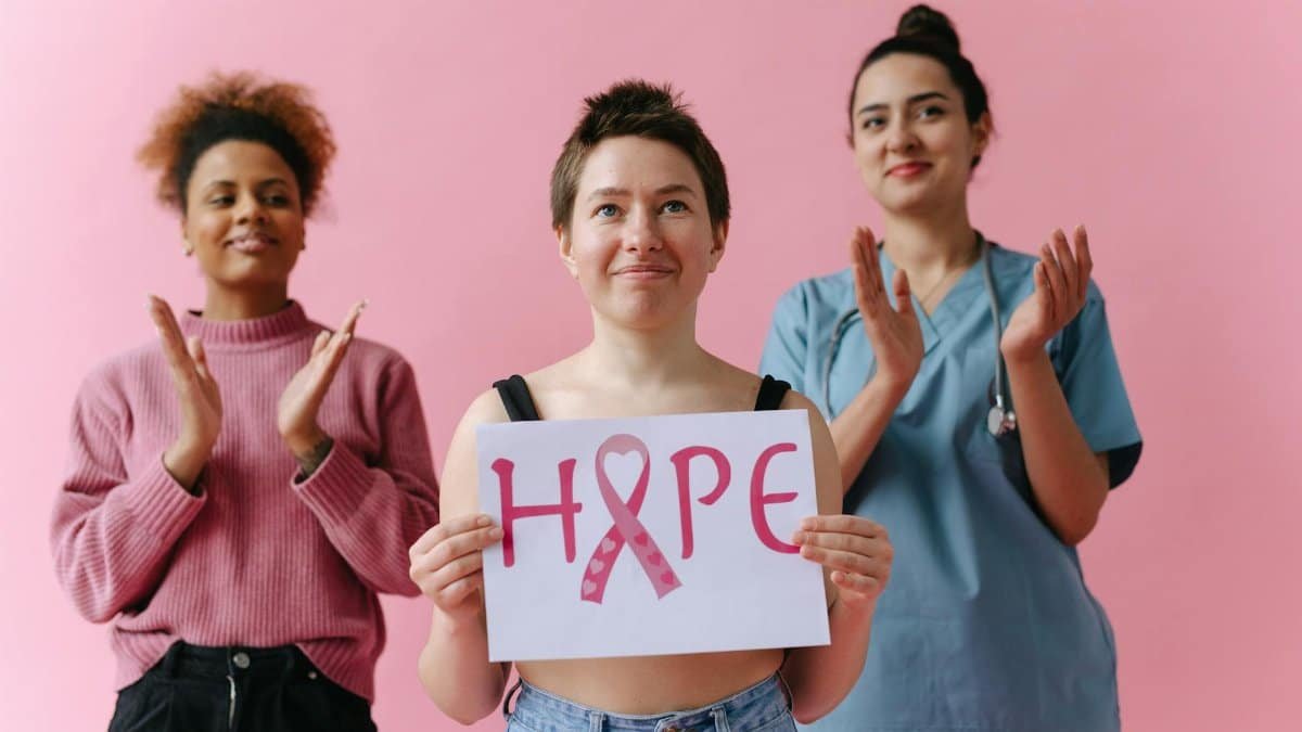 Three women show hope and support for breast cancer awareness, one holding a 'hope' sign.