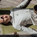 Man lying on yoga mat with healing crystals during meditation for relaxation and balance.
