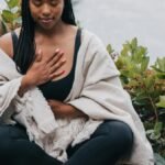 A woman practicing mindful meditation outdoors by the water, symbolizing wellness and relaxation.
