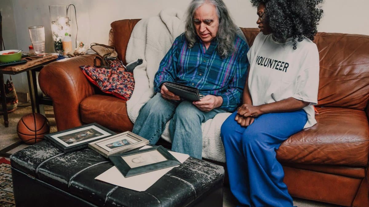 An emotional bonding scene between volunteers on a cozy sofa with family photos.