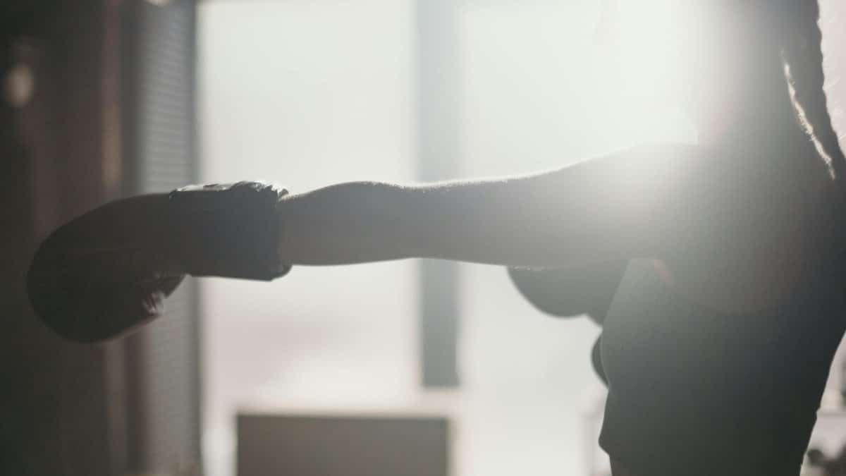 Silhouette of a female boxer throwing a punch in sunlight, capturing strength and focus.