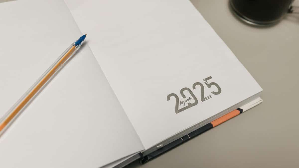 Open 2025 planner with a pen and coffee cup on a desk, ideal for productivity themes.