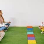 Kids and teachers in a preschool yoga session practicing mindfulness indoors.