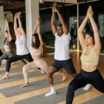 A diverse group practicing yoga with raised arms in an indoor studio setting.