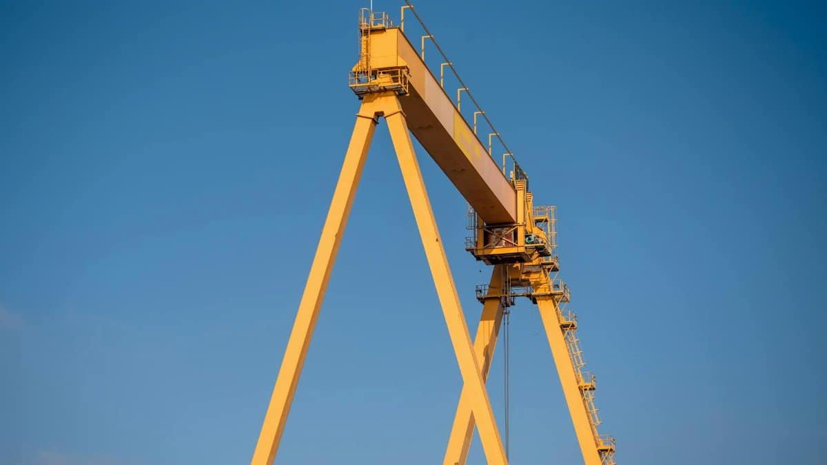 A large yellow crane stands tall against a clear blue sky, showcasing industrial strength.