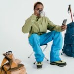 An adult hiker sitting and enjoying a coffee break with backpacking gear indoors.