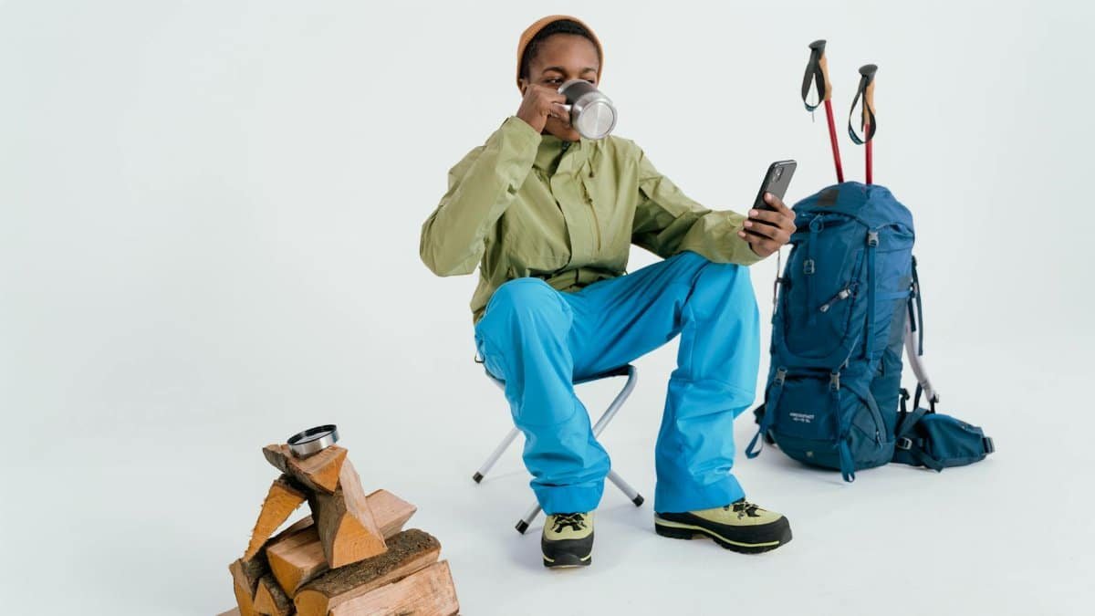 An adult hiker sitting and enjoying a coffee break with backpacking gear indoors.