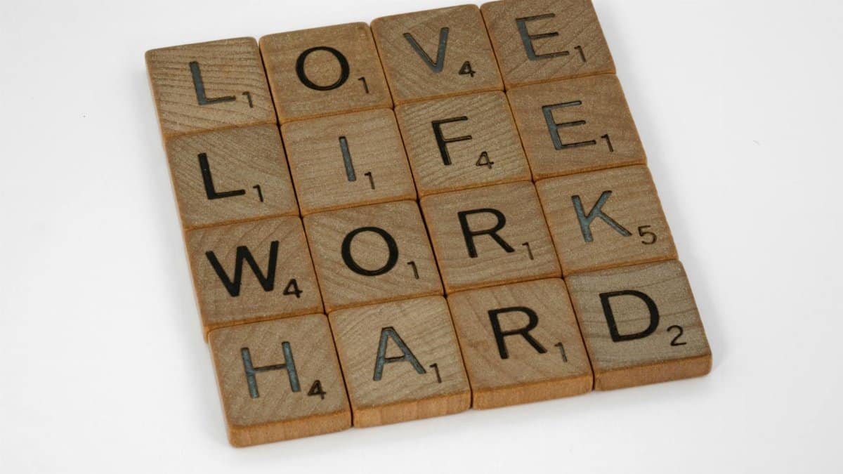 Scrabble tiles spelling 'Love Life Work Hard' on a white background, conveying motivation.