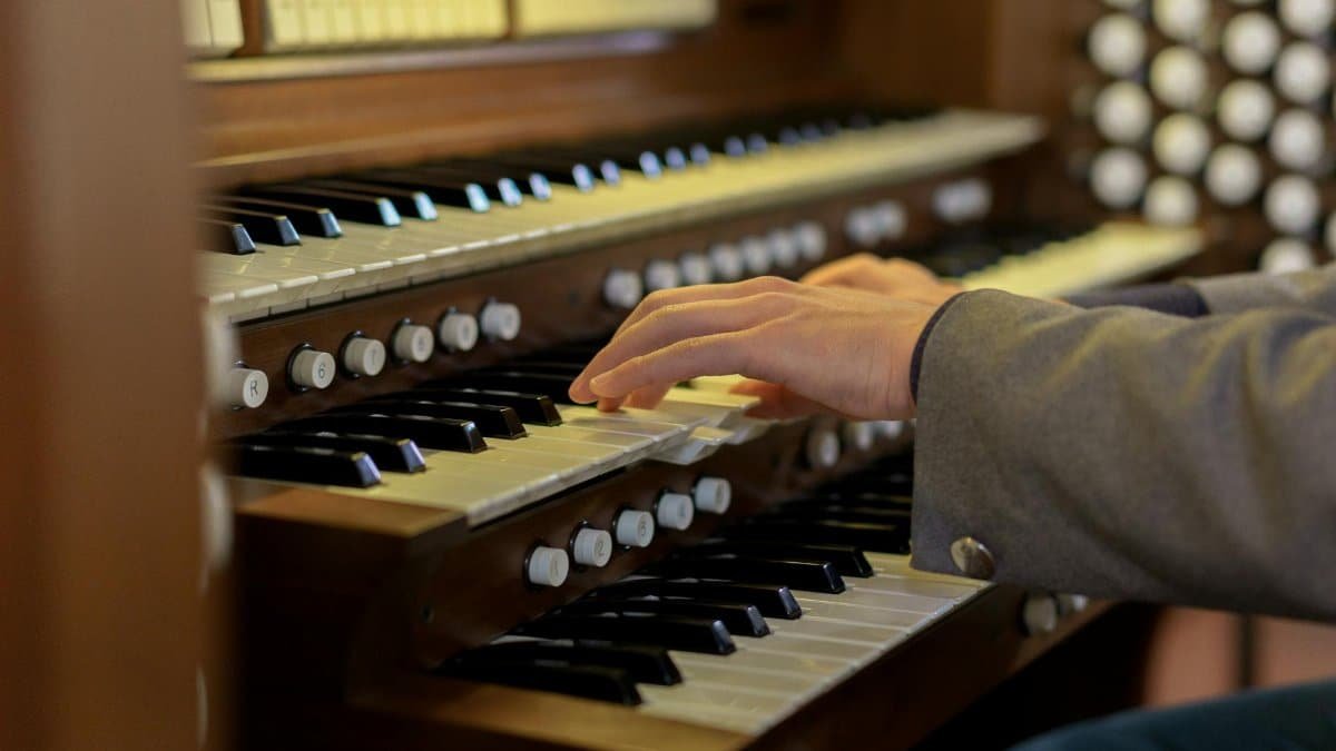 Musician's hands skillfully playing a classical church organ keys in close-up view.