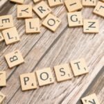 Wooden scrabble tiles scattered with the word 'POST' on a rustic wooden surface.