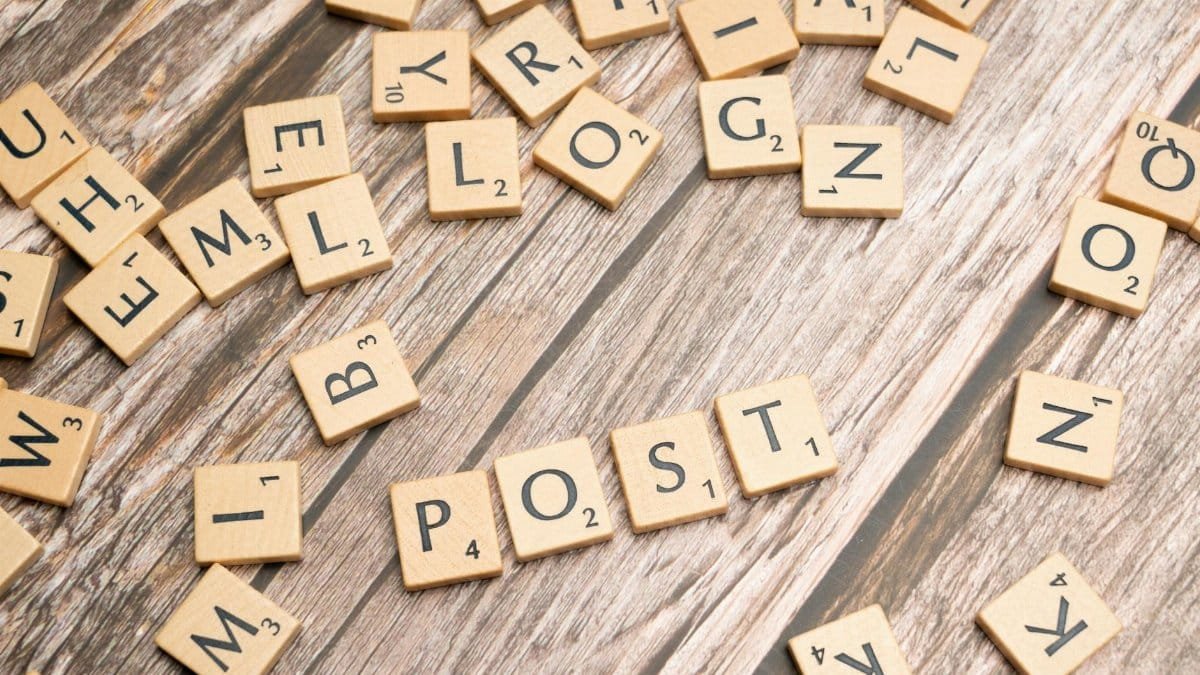 Wooden scrabble tiles scattered with the word 'POST' on a rustic wooden surface.