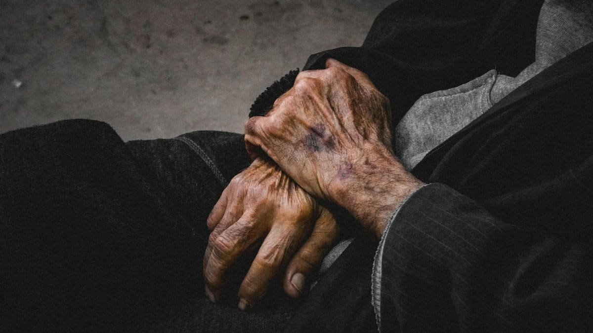 A close-up of elderly hands clasped together, showcasing age and resilience.