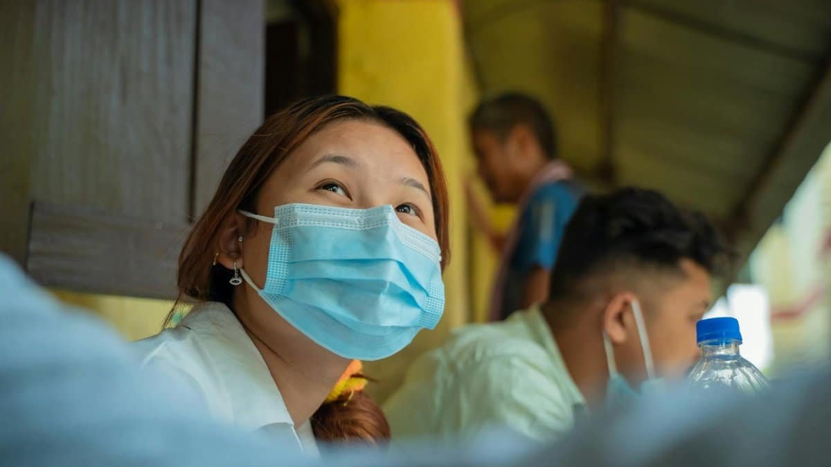 Woman looking up while wearing a face mask, embodying protection and awareness in an outdoor setting.