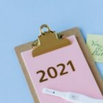 A positive pregnancy test on a clipboard marked 2021, with a note saying 'You, me & Baby!' and a tulip, symbolizing new life.