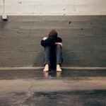 A person sitting alone in a corner, evoking themes of solitude and emotion.