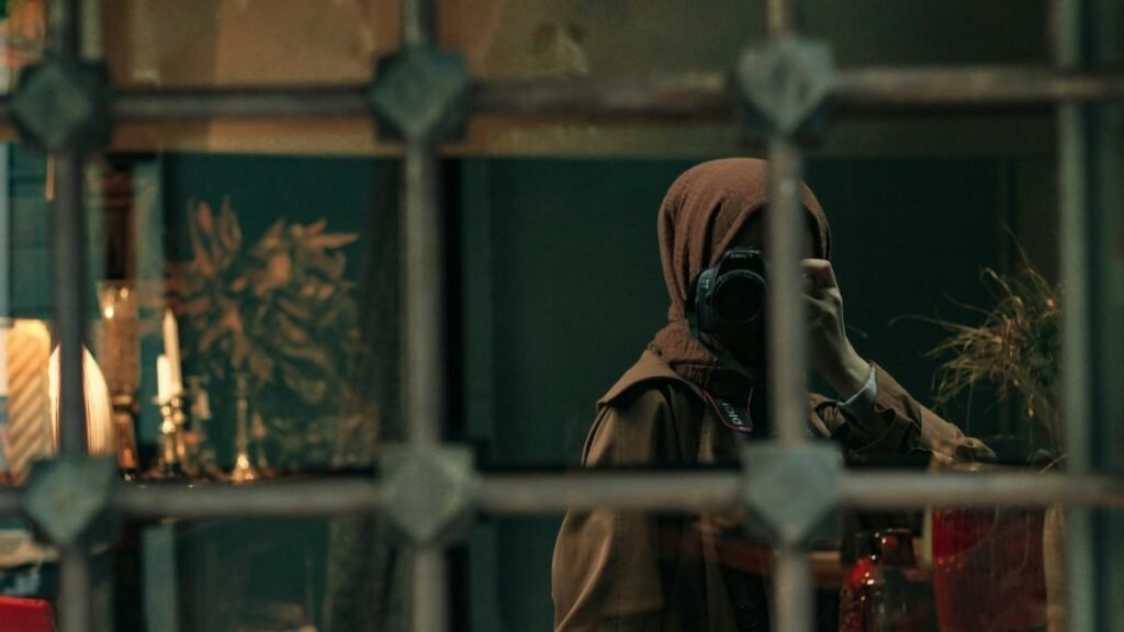 A photographer captures a self-portrait through a cafe window reflection, creating a mystique atmosphere.