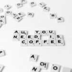 Scrabble tiles spell out 'All You Need Is Coffee' on a white background, offering a creative still life.