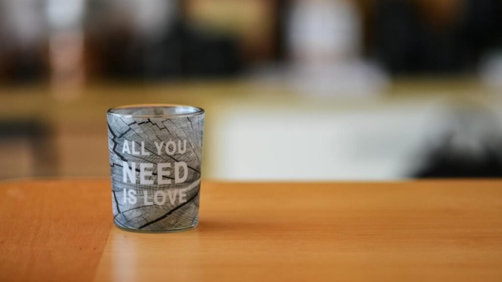 A close-up of a glass cup with 'All You Need is Love' text, ideal for lifestyle themes.