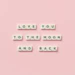 Letter tiles spelling 'Love You to the Moon and Back' on a pink background.
