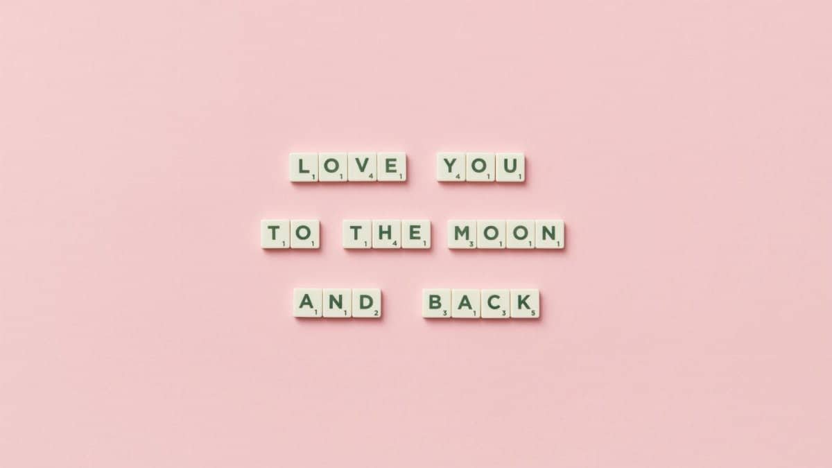 Letter tiles spelling 'Love You to the Moon and Back' on a pink background.