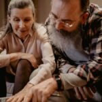 An elderly couple enjoys looking at an album, reminiscing about happy past moments.
