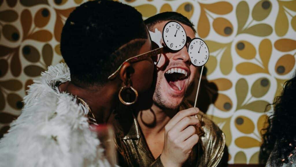 A joyful New Year's Eve party featuring friends in glamorous attire, celebrating indoors.