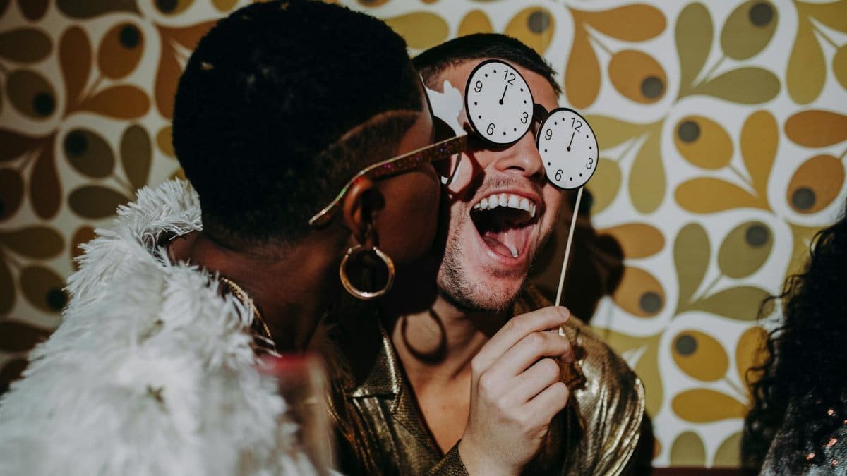 A joyful New Year's Eve party featuring friends in glamorous attire, celebrating indoors.