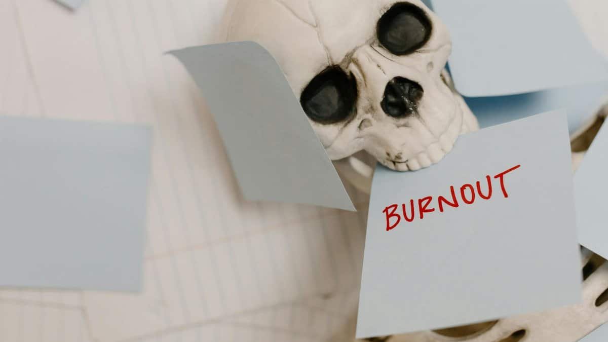 Skeleton surrounded by sticky notes symbolizes burnout and exhaustion in a dramatic setup.