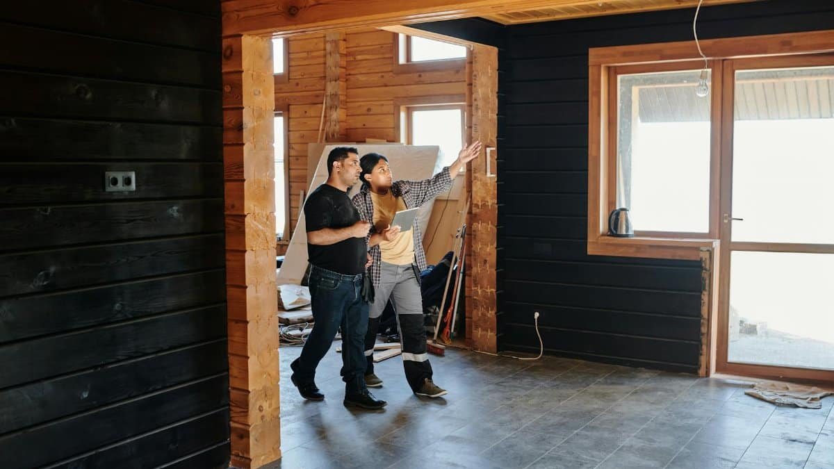 Two adults discussing home renovation in a partially constructed modern wooden interior.